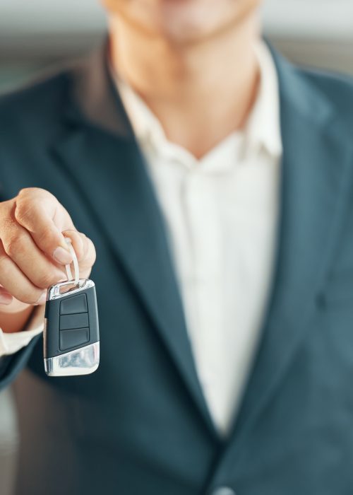 Cropped image of car dealership salesman giving keys
